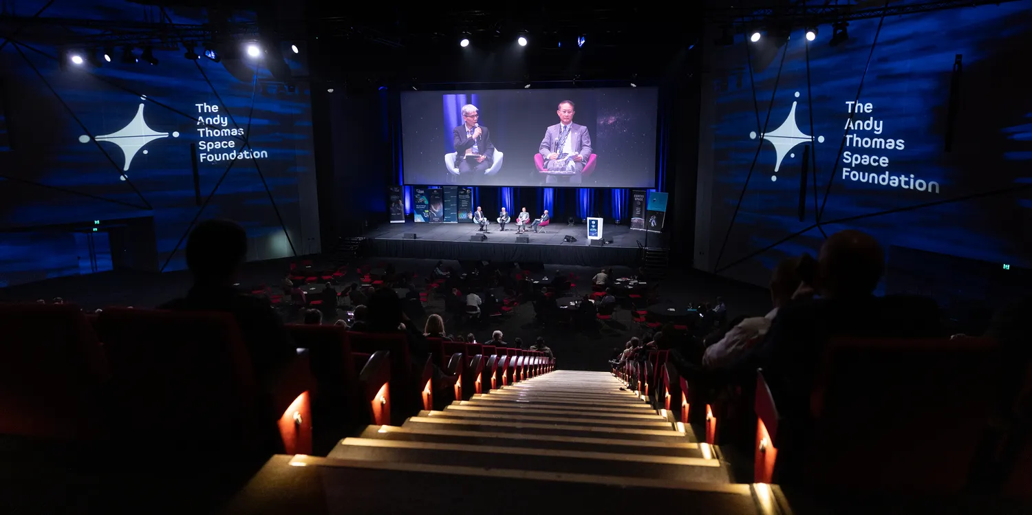 Panel of speakers on stage at the Australian Space Forum with The Andy Thomas Space Foundation branding projected on the walls